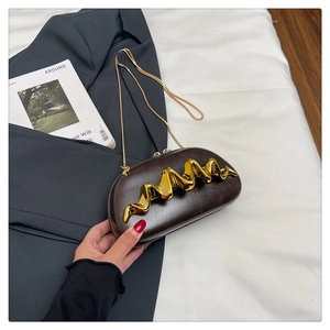 Macro shot of dark brown moon-shaped evening clutch with wavy gold metal trim and chain
