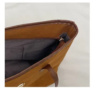 Close-up detail of the smooth zipper closure and gray interior lining on the brown tote bag