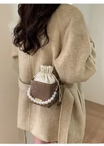 Detailed view of a brown box bucket bag with white drawstring insert and pearl handle