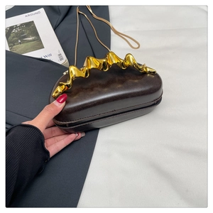 Detail of dark brown leather evening bag featuring a gold wavy metal handle and chain strap