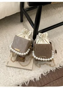 Detail of elegant pearl handle and drawstring closure on texture brown bucket bag