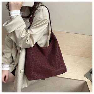 Detail view of burgundy leopard print tote bag worn as a stylish underarm hobo shoulder bag