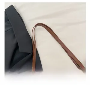 Close-up of brown faux leather shoulder straps with detailed stitching on tote bag