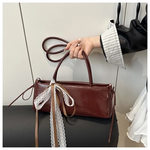 Detail of burgundy leather baguette bag with white lace and brown ribbon bow decoration