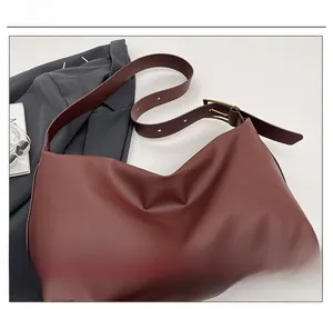 Detail of adjustable wide strap and vintage gold buckle on burgundy hobo shoulder bag
