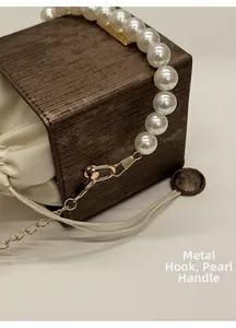 Detail of elegant gold hardware hook and white pearl handle on brown bucket bag