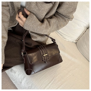 Close-up of vintage dark brown shoulder bag featuring contrast stitching and metal buckle