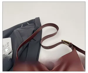 Adjustable strap detail of a burgundy leather shoulder bag with vintage gold buckle