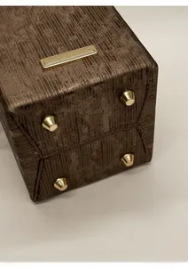 Detail of brown textured handbag base featuring four protective golden metal feet studs