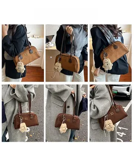 Detail einer braunen Wildleder-Bostontasche mit Teddybären-Anhänger und feinen Riemen