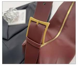 Detail of the high-quality bronze metal buckle on a luxury dark red leather tote bag