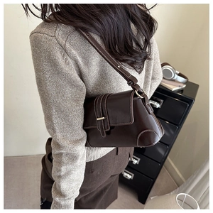 Detail of dark brown glossy leather shoulder bag with vintage buckle and contrast stitching