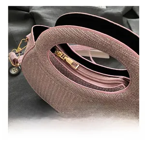 Close-up of mauve woven glitter fabric handbag with gold zipper and curved handle