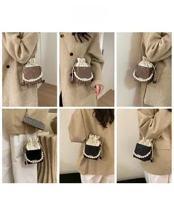 Detail of elegant crossbody bag with pearl handle, drawstring pouch, and metal chain strap
