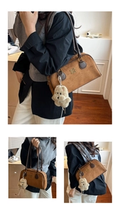 Detailansicht der braunen Wildledertasche mit Metalllogo und niedlichem Bärenanhänger