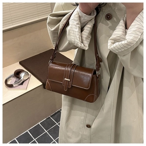 Detail of vintage dark brown faux leather handbag with contrast stitching and gold buckle