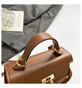 Close-up of brown leather handbag featuring gold metal clasp and precise stitching