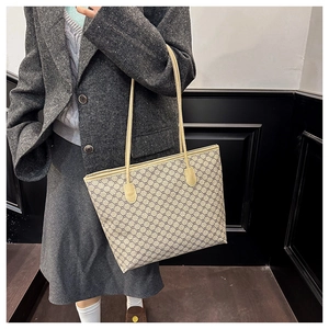 Detail of large tote bag with classic pattern and beige handles on a model's shoulder