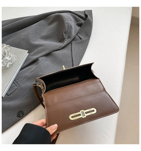 Detail view of the open brown vintage crossbody bag with golden buckle and black lining
