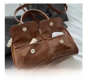 Detail of vintage brown leather handbag exterior pockets with pearl strap and magnetic clasp