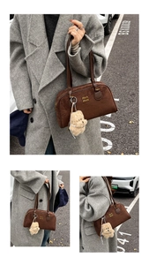 Detail einer dunkelbraunen Wildlederhandtasche mit Plüsch-Hundeanhänger und Goldlogo