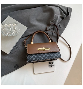 Close-up of vintage patchwork handbag with gold metal lock and brown leather handle