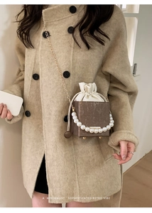Close-up of brown textured bucket bag with gold chain and large pearl strap detail