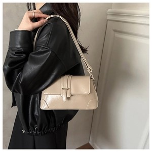 Detail of glossy beige shoulder bag featuring a metallic buckle and adjustable strap