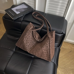 Large leopard print tote bag for women made of textured fabric on a black leather bench