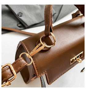 Detailed side view of dark brown leather handbag with gold twist lock and shoulder strap
