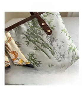 Detail of vintage tote bag with green bamboo embroidery and stylish silk scarf wrap
