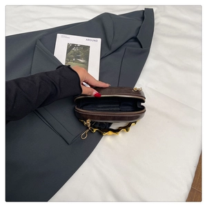 Dettaglio di una mini borsa da sera marrone con manico in metallo dorato e interno borsa