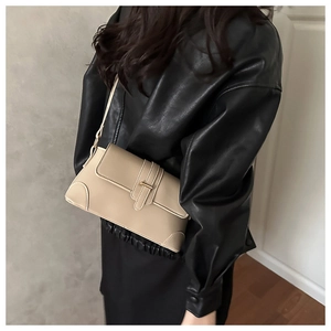 Close-up of light beige baguette bag with contrast stitching and leather strap buckle
