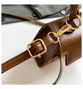 Close-up of brown leather bag strap with adjustable gold buckle and lobster clasp hardware