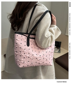 Detailed texture of pink tote bag featuring black bow patterns and pleated fabric design
