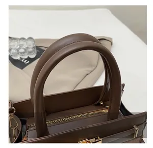 Détail du sac à main en cuir marron avec ferrures dorées et coutures précises