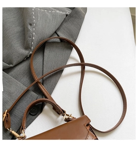 Detailed view of brown leather handbag with leopard print sides and adjustable straps