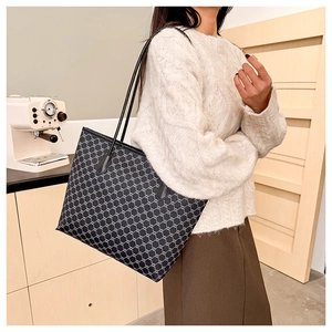 Detailed view of large tote bag with classic pattern held by model in cozy interior