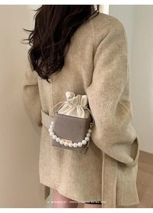 Close-up of gray textured bucket bag with pearl handle and chain shoulder strap