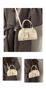 Three-way view of a cream motorcycle shoulder bag with pearl bow and heart charms