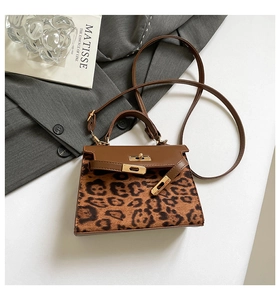 Detail view of leopard print texture and golden twist lock on the brown leather handbag