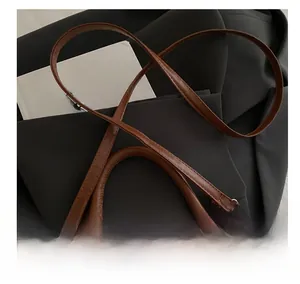 Detail view of brown leather and woven shoulder bag with gold geometric metal hardware