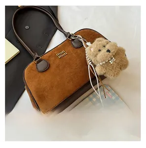 Nahaufnahme der braunen Wildleder Boston Tasche mit Logo und Plüschtier Anhänger