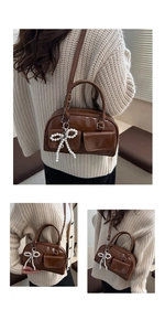 Close-up of deep brown patent leather bag with vintage pockets and pearl bow charm