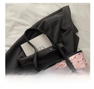 Detail of pink textured tote bag featuring 3D pleats and black bow accents with soft handle