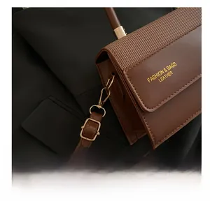 Close-up of brown patchwork small square bag with golden hardware and leather strap