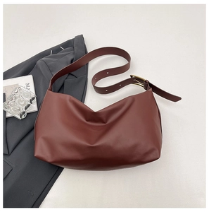 Detail of dark red hobo bag with vintage gold buckle on wide strap and matte leather texture
