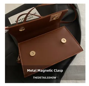 Detail view of brown leather bag showing secure golden magnetic snap button closures