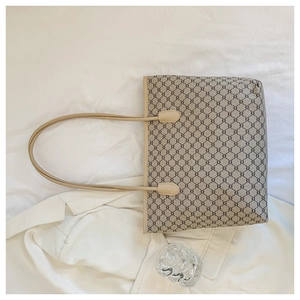 Top view of large tote bag with geometric monogram pattern and leather handles
