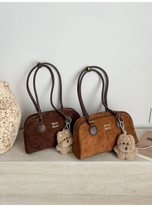 Detail der Wildleder-Boston-Taschen mit Goldlogo, Plüsch-Anhängern und Schultergurten